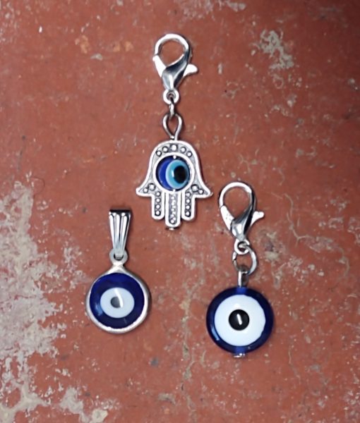 three evil eye necklace charms on red brick background
