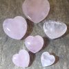 rose quartz hearts in a range of sizes on a wood background