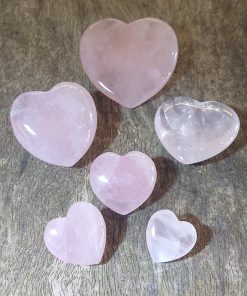 rose quartz hearts in a range of sizes on a wood background