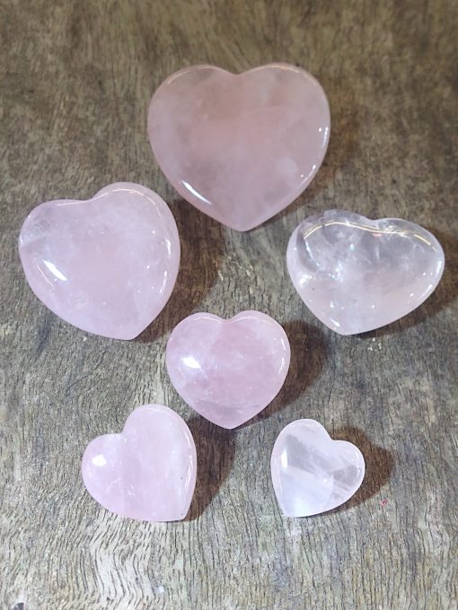 rose quartz hearts in a range of sizes on a wood background